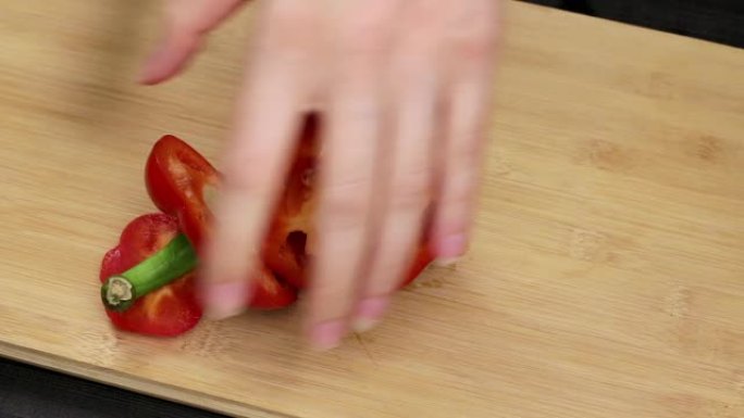 大红甜椒被分离出来，核心被去除。厨师将一把刀握在女性手中，切一种健康的蔬菜。关闭