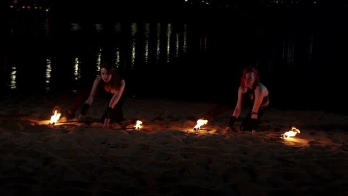 女性杂耍者举起躺在沙滩上的火把