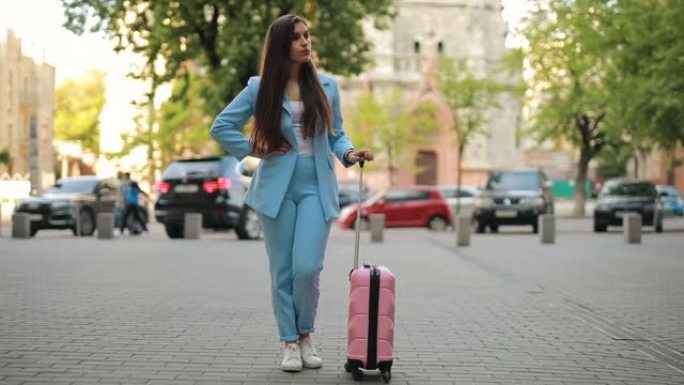 女人带着手提箱在城市等待出租车