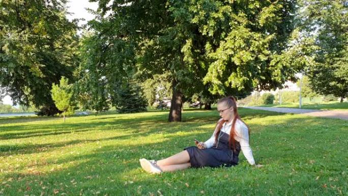 午餐时间在公园里用智能手机生活的女学生