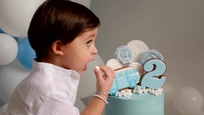 两岁的男孩用汽车吃节日的蓝色蛋糕