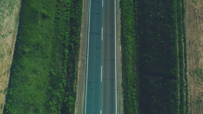 空中模糊的视图，不同类型的汽车沿着空碎石路行驶，穿过绿色的草地和农田景观。4K。