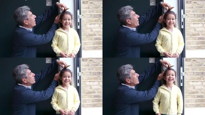 一位父亲在家里的墙上测量他的小女儿，看看她有多高