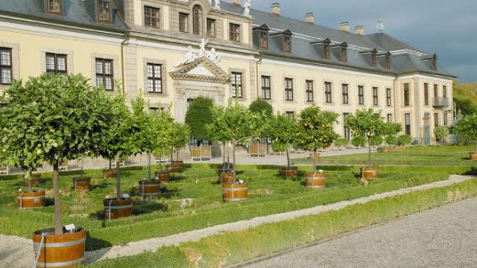 德国汉诺威。在美丽的中世纪宫殿附近种植了柑橘和橘子的树林。手持地图的年轻女游客进入框架。回去。慢动作