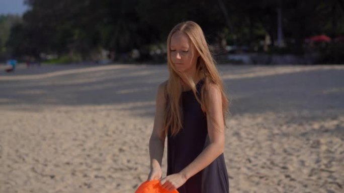 热带海滩上的年轻女子给充气沙发充气。暑假概念