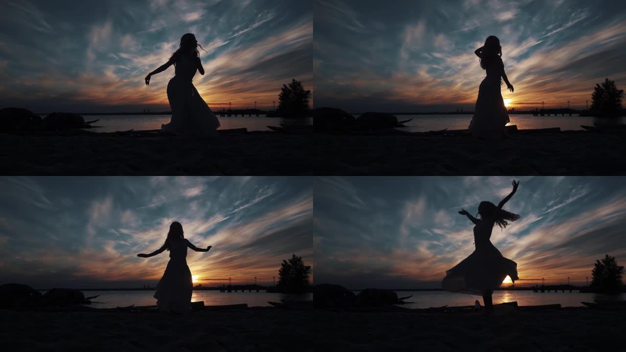 日落时，舞动的芭蕾舞演员在天空的剪影。优雅的女孩在海边跳舞。
