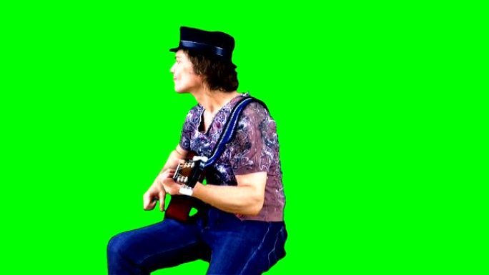 戴着帽子的酷摇滚吉他手在色键上弹奏原声吉他。音乐家在绿色背景下表演。