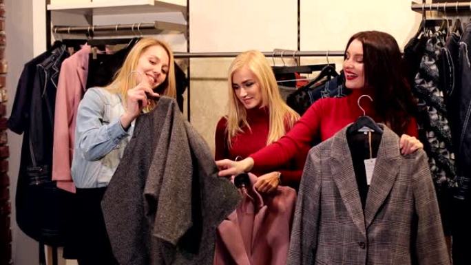 三个女孩在一家大型购物中心的时装店买新衣服。