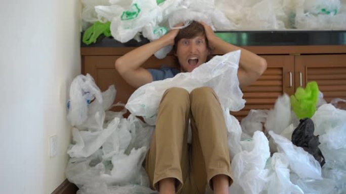 一个年轻人被塑料袋覆盖着，对他使用的塑料数量感到震惊。塑料污染环境的概念。塑料过度使用的概念