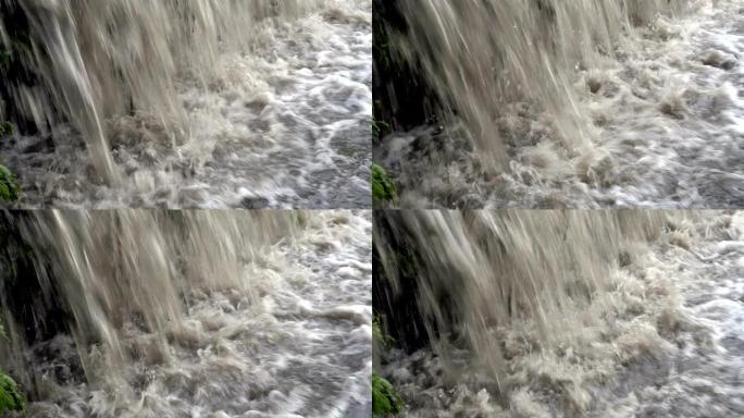 极度接近汹涌的浑浊冒泡水涌入河中。小瀑布。特写。4K。