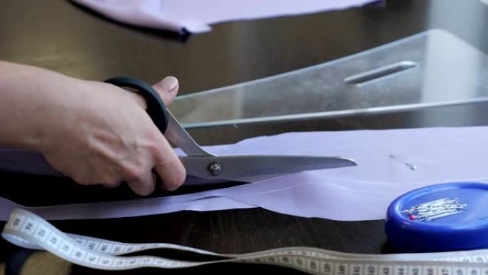 裁缝裁切布使用剪刀跟随粉笔标记的图案，特写手。
