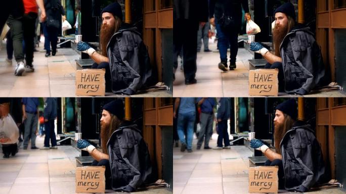无家可归的人带着 “mercy” 纸板，在拥挤的街道上乞讨