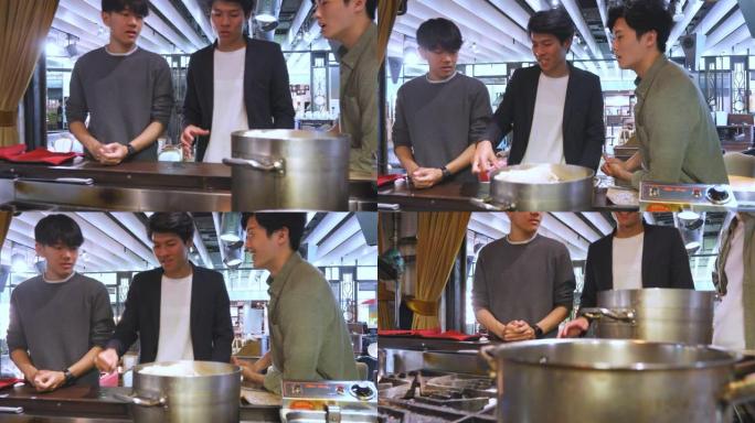 年轻的亚洲男子观看在餐厅烹饪的食物