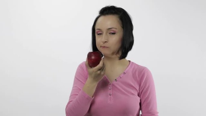 年轻漂亮的女人在白色背景上吃又大又新鲜又多汁的红苹果