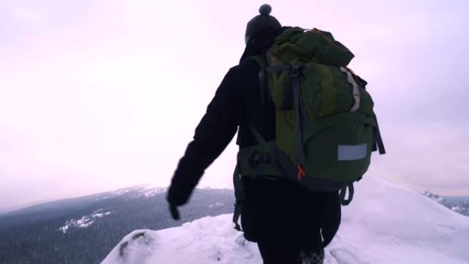 一个年轻人，一个游客，站在白雪皑皑的山边，敬佩山顶。