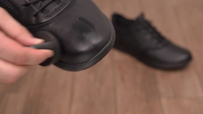 前景中男性手握和清洁黑色皮鞋的特写镜头。模糊背景上的休闲风格干净鞋子。