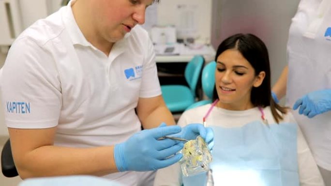 男性牙医向一位女士患者展示牙科设备上的牙齿问题