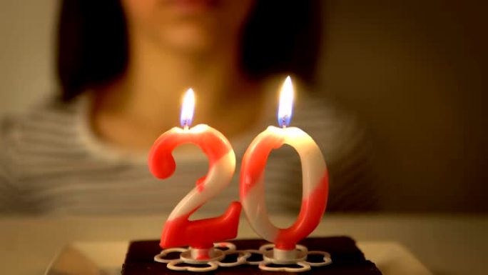 女孩在纸杯蛋糕上吹出20岁生日蜡烛