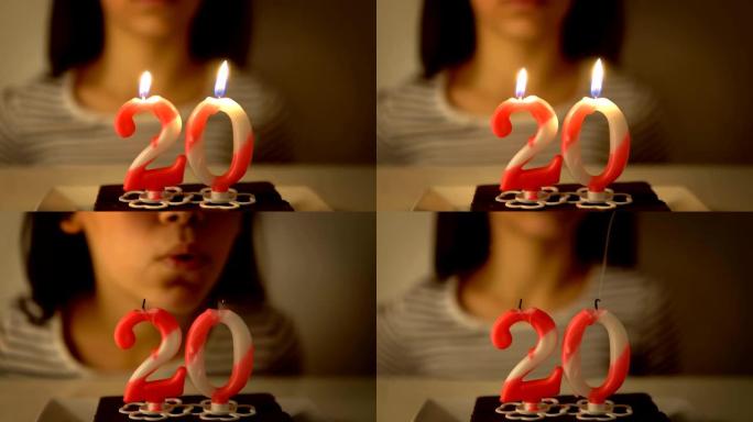 女孩在纸杯蛋糕上吹出20岁生日蜡烛