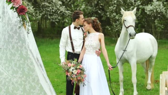 新娘与新郎和白马在他们的身边，婚礼帐篷和桌子装饰得很充分。
