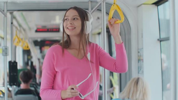 年轻女子在现代电车中移动时握着把手。在公共交通工具上享受旅行的快乐乘客。