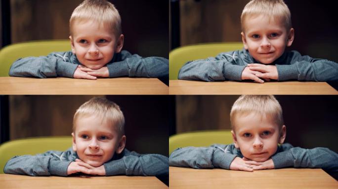 快乐的小男孩坐在房间的木桌旁。
