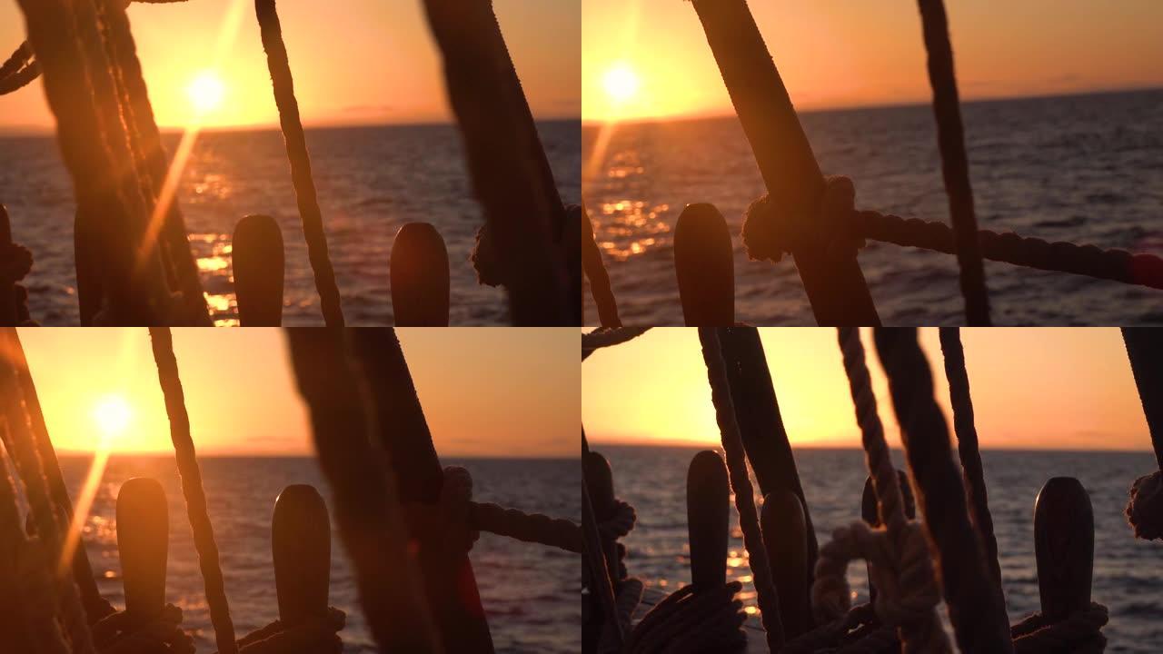 日落穿过一艘旧帆船的护罩和索具。海景慢动作视频