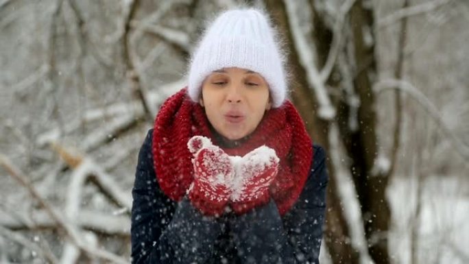 穿着白色针织帽，红领巾和连指手套的年轻女孩吹雪