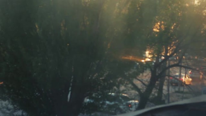 散焦夜城，汽车交通灯。日落日模糊的画面。小雨在窗户上留下水滴。汽车在路上行驶并站立。
