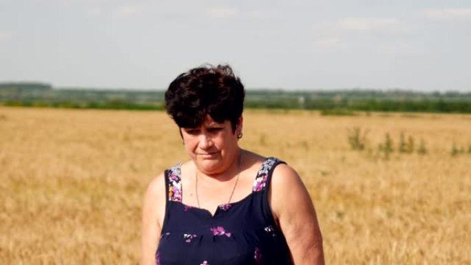 一名农村妇女站在麦田里的小麦中