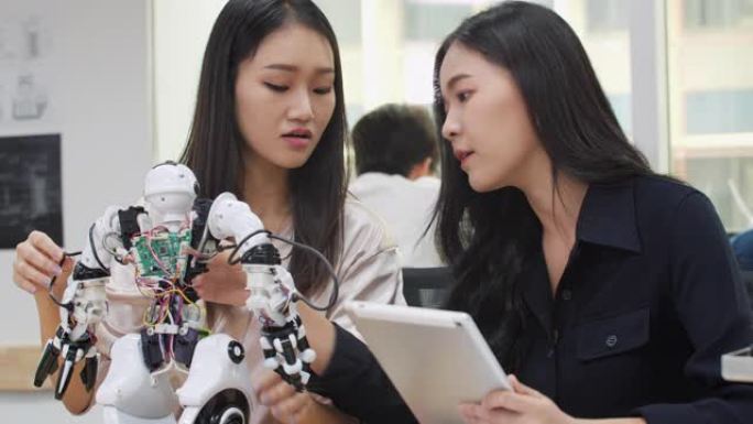 亚洲女工程师在实验室组装和测试机器人反应。建筑师设计电路会议共享技术思想和协作开发机器人。