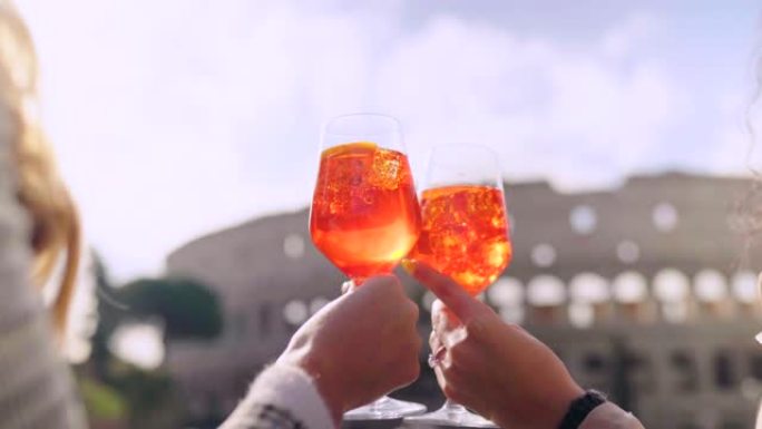 在罗马斗兽场的背景上拍摄两杯装满橙色鸡尾酒的特写镜头