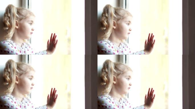 小女孩悲伤地凝视着窗外。坐在窗台上。孩子看着窗外。