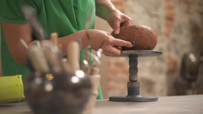 专业陶工使用特殊工具在旋转支架上成型和成型陶瓷锅的特写镜头。在工作室工作的艺术家。传统雕刻。手工制作