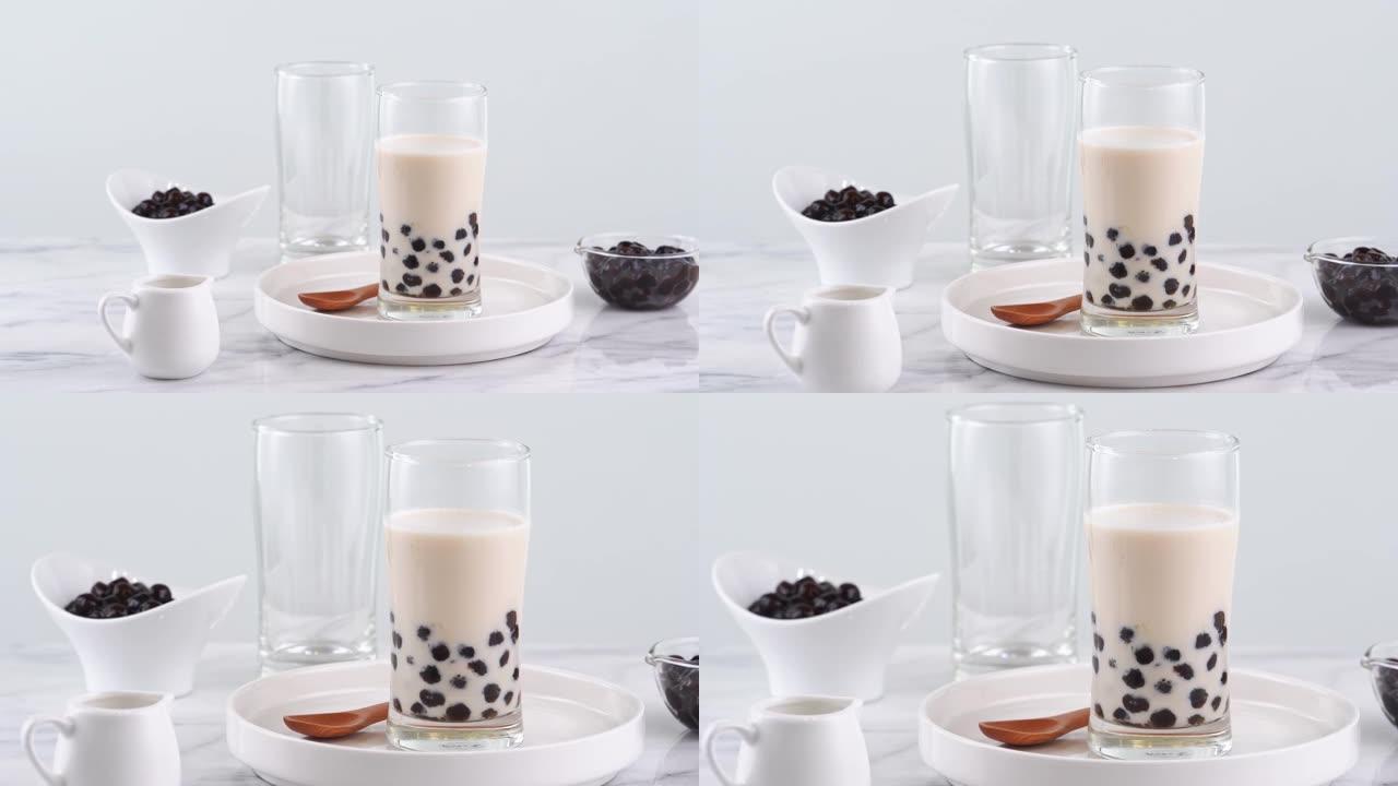 美味的木薯珍珠玻璃奶茶，明亮的大理石桌子和白色托盘上的台湾流行饮料，自制概念。4k放大拍摄视频