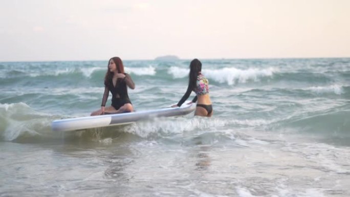 亚洲女性泳装在海滩上玩冲浪板，年轻女孩在海滩上穿着比基尼和冲浪板