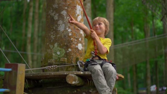 在森林探险公园的一条路线上，一个小男孩穿着安全带拍摄了一个超级镜头。户外娱乐中心，为成人和儿童提供爬