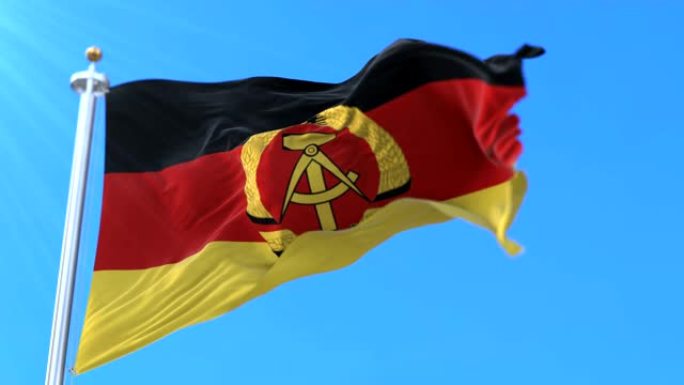 在蓝天中挥舞的德意志民主共和国或东德国旗。循环