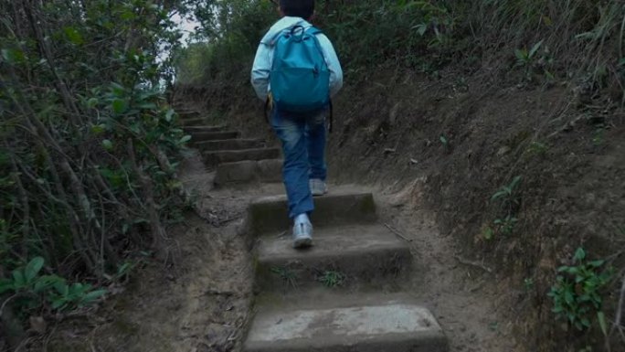 亚洲男孩沿着山路徒步旅行