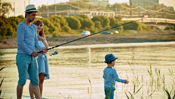 家庭钓鱼-父亲钓鱼-他的妻子抱着一个婴儿-小男孩在海滩上散步
