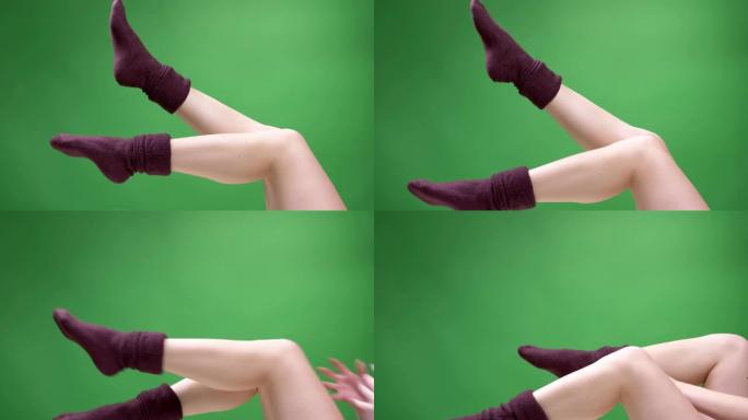 特写侧视图拍摄的女性少女腿穿着可爱的红色短袜嬉戏地移动，背景孤立在绿色上