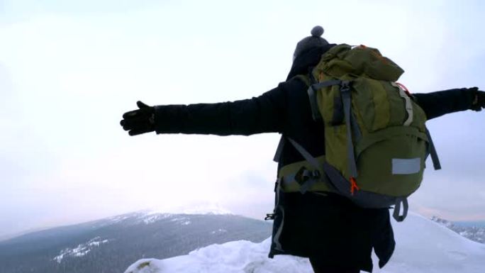 一个年轻人，一个游客，站在白雪皑皑的山边，敬佩山顶。