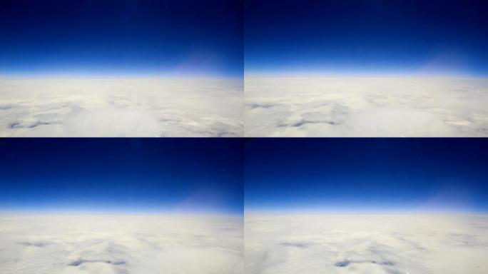 在云层上方乘飞机旅行。通过飞机窗口查看。通过卷云和积云以及很少的湍流飞越瑞士阿尔卑斯山，显示出地球的