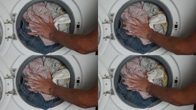 洗衣机里装满了衣服。该男子试图将衣物密封在洗衣机的水箱中。