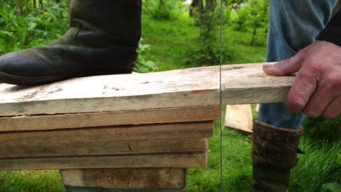 木匠正在锯木板。用钢锯看到了木板。缩短木板。