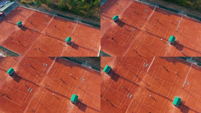 在阳光明媚的夏日，无法识别的网球运动员在橙色球场上打网球的鸟瞰图