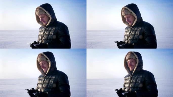 站在冰冻的湖上的商人用信用卡和智能手机付款，转向相机微笑。