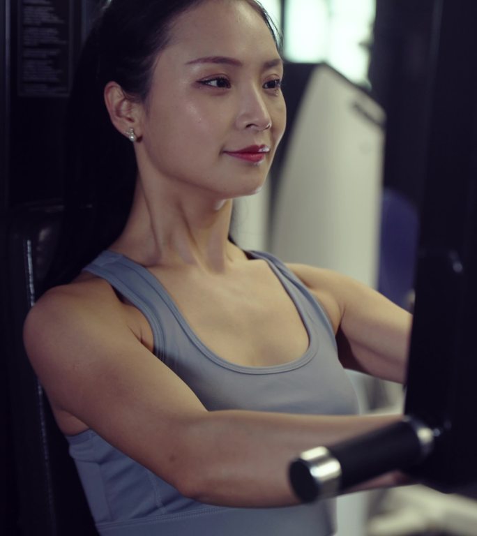 女性穿运动内衣在健身房使用哑铃锻炼