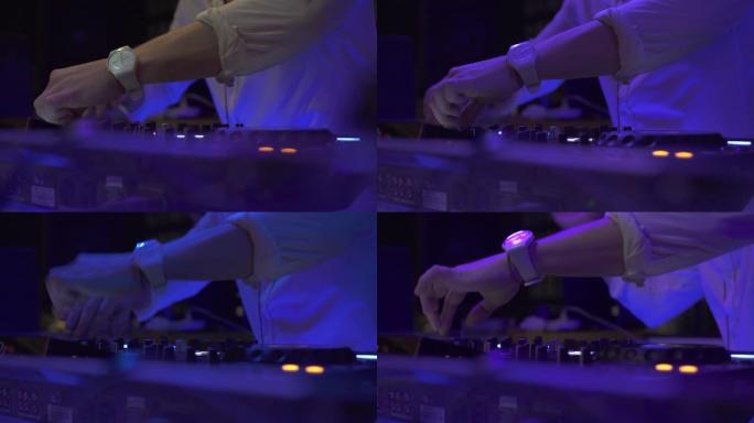 Dj在夜总会五颜六色的灯光下在音响控制台上播放音乐。迪斯科派对的DJ混音器和音乐控制台。彩色照明的唱