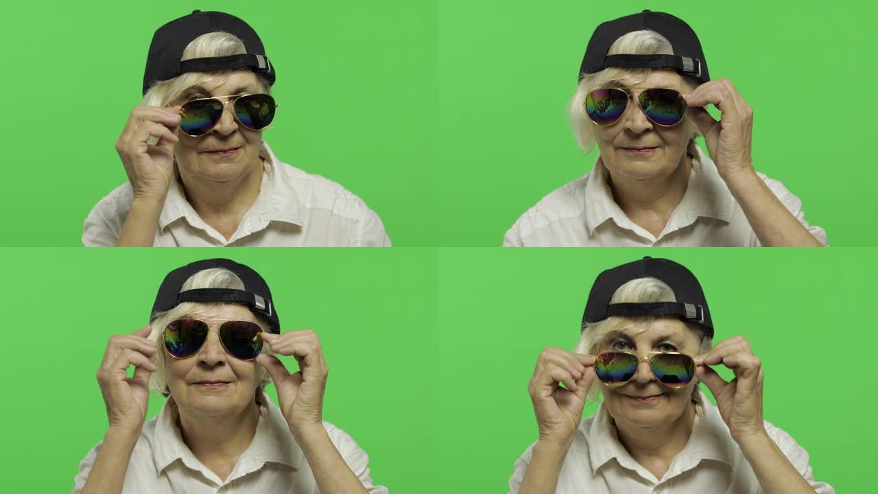 一位戴着墨镜和帽子的老妇微笑着。老奶奶。色度键